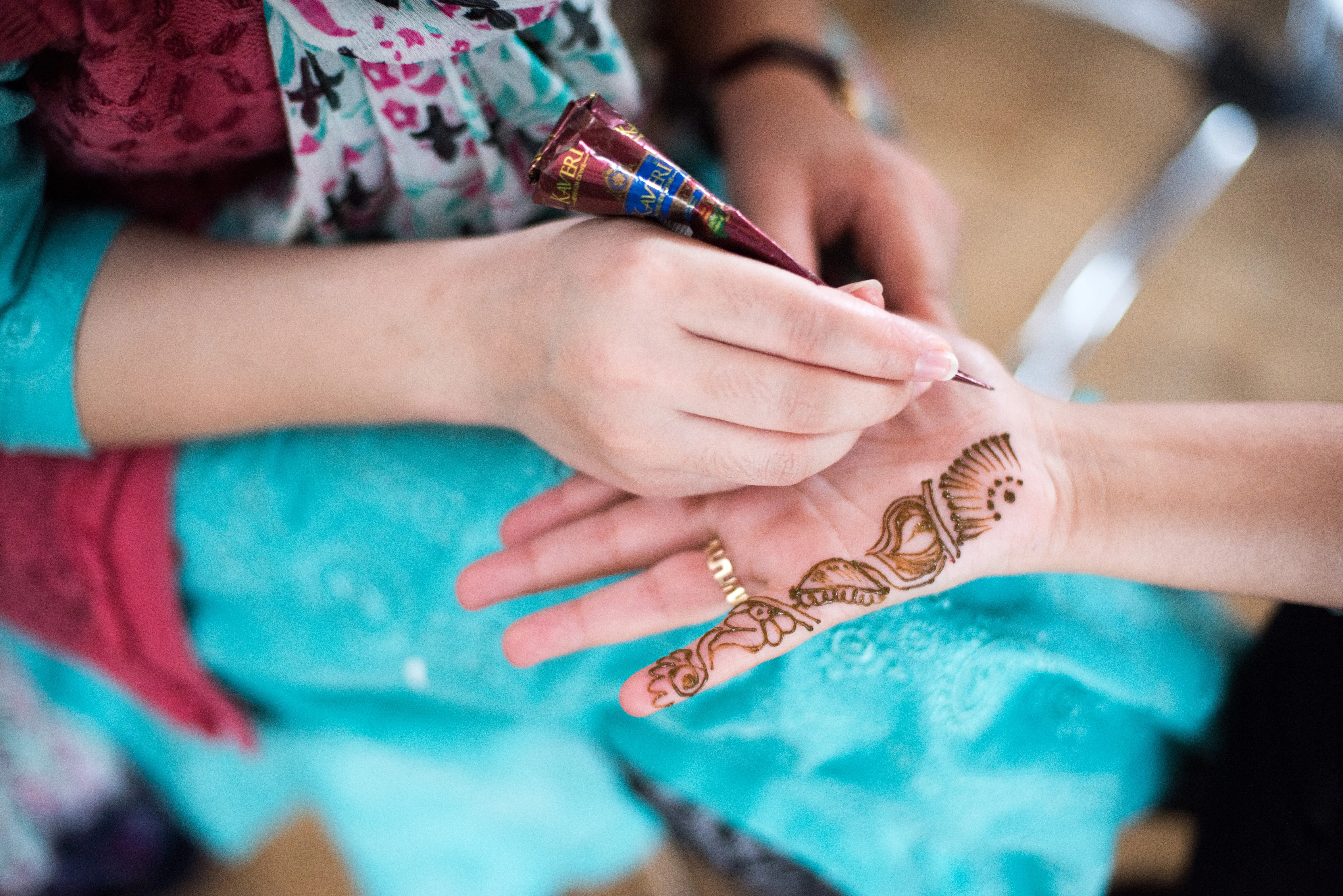 A person is drawing a beautiful henna drawing on someone's hand